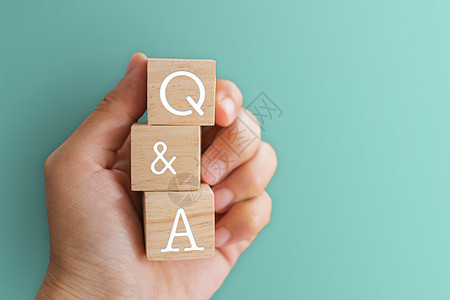 在木制立方体上 用有背景的手握着Q和字母表 问答的含义学习商业帮助教育社区教学网络顾客论坛服务图片