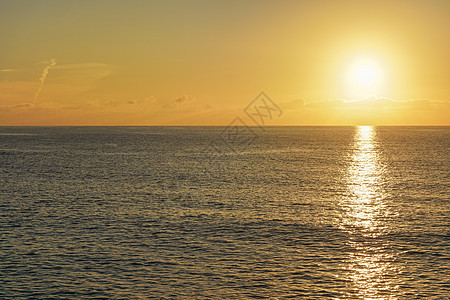 太阳在平静的海面上空升起 云彩色为橙色图片