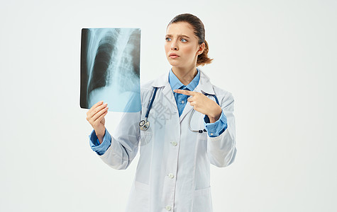 身穿医疗长袍的医生 带着X光照片 用手拍着探照职业诊所工作骨骼考试药品疾病女性检查医师图片