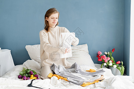 青年妇女在家里的床上整理衣服 安排她们穿的衣服壁橱女性家庭清洁度毛巾回收折叠卧室衣柜小样图片