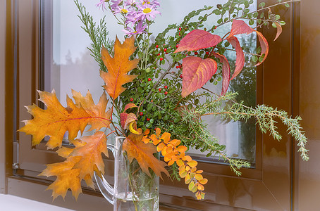 秋天的花朵和窗台上的叶子周年生活季节花瓣窗户纪念日橙子花瓶假期菊花图片