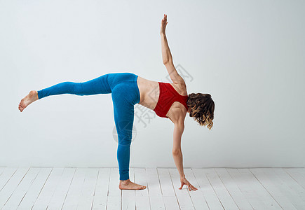 女人站在一条腿上 在一间明亮的房间和长成的瑜伽女士身体健身房冥想姿势活动福利白色力量成人图片