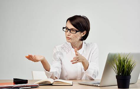 坐在她桌上的女士在笔记本电脑办公室经理面前戴着眼镜 穿着眼镜微笑管理人员电话人士女性商务工作工人女孩职场图片