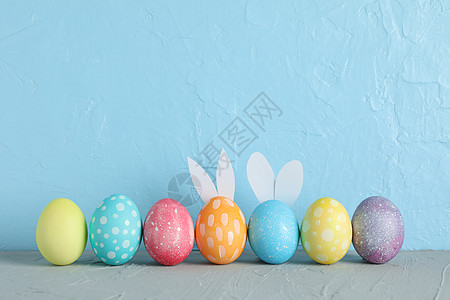 复活节彩蛋和可爱小兔子耳朵按颜色背景放在桌边的彩色背景收藏装饰团体兔子传统橙子假期季节庆典蓝色图片