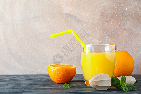 玻璃杯 有新鲜橙汁和管子 橘子 薄荷和木质果汁 放在木制桌边的彩色背景 文字空间上木头情调异国作品水果榨汁机木板食物橙子桌子图片