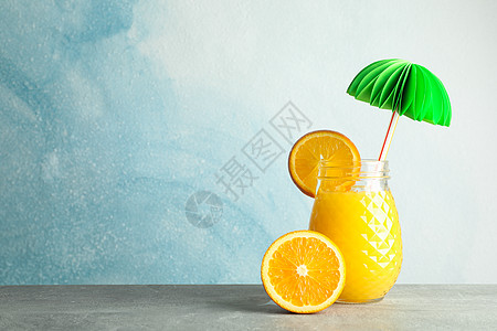 玻璃罐 有新鲜橙汁 装饰性棕榈和橘子 灰色桌面 彩色背景 文字空间水果橙子桌子饮料作品饮食情调果汁木板榨汁机图片