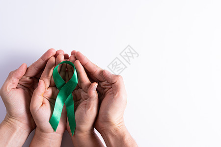 世界肾日 男女手握着对肾病的绿丝带认识 孤立白种背景 16治疗帮助药品活动病人幸存者丝带压力研究世界图片
