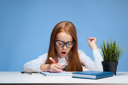 带眼镜的红发红头发女孩在课桌学校教育做功课女性童年幼儿园婴儿课堂孩子思维瞳孔绘画笔记本图片