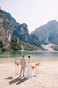 新娘和新郎在意大利的背景下 以秋花柱为拱门站立了仪式 欧洲的目的地婚礼 在Braies湖上举行夫妻套装微笑分支机构新婚捧花幸福袖图片