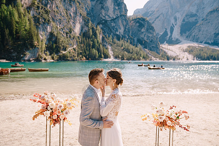 新郎在婚礼场地为新娘戴上戒指 在意大利的背景下 以秋季花柱拱形为背景 欧洲的目的地婚礼 在 Braies 湖干花湖泊蕾丝玫瑰分支图片