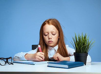 女孩坐在学校课桌边上上课并进行生活方式教育幼儿园瞳孔孩子婴儿艺术家庭作业情感绘画学习笔记本图片