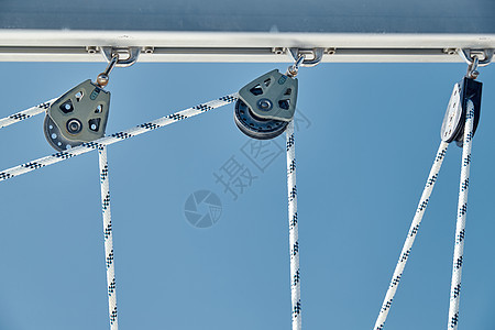 阳光明媚的天气下 帆船绳索的特写视图 桅杆上的滑轮和绳索 游艇运动 船舶设备 大海是背景索具假期队长绞盘工作晶石水手们蓝天蓝色电背景图片