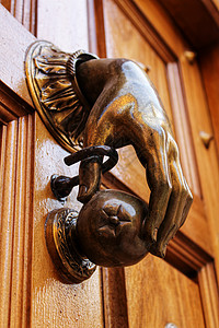 旧木制门上有手形状的金敲门机青铜木头装饰品古董入口宏观黄铜门把手金子装饰图片