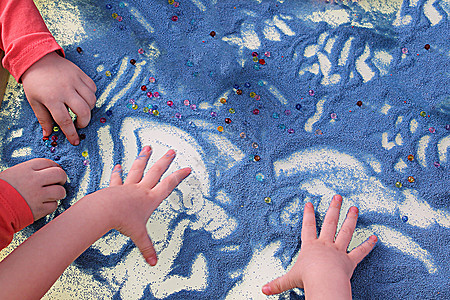 儿童双手在白桌沙沙疗法上触摸蓝色沙子 发展精巧的机动技能图片