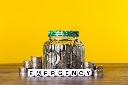 黄色背景玻璃瓶中的很多硬币 为储蓄而储蓄的概念商业现金情况房子保险基金标签生活投资退休图片