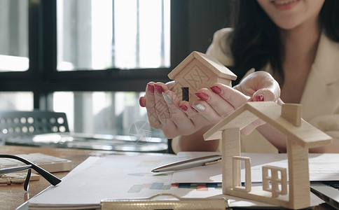 用房屋模型手特写房地产经纪人 将签署合同签署的适度协议形式放在办公室 概念房地产搬家或出租物业图片
