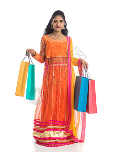 美丽的印度年轻女孩穿着传统民族服饰提着购物袋 在白色背景上被隔离胜利节日店铺销售震惊女士冒充女性顾客裙子背景