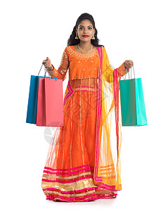 美丽的印度年轻女孩穿着传统民族服饰提着购物袋 在白色背景上被隔离女性女士销售冒充顾客胜利购物狂裙子震惊店铺背景