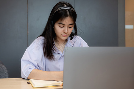 工作中的女孩亚洲学生在家用笔记本电脑在线课程中做笔记的亚洲学生女孩学校视频工作成人女士教育大学休闲装互联网背景