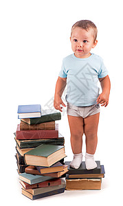 男孩站在一堆书的书架上 作为教育肖像     孤立于白色背景之上教科书学者男性图书幼儿园学习快乐学生学校男生图片