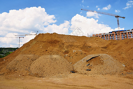 沙堆和建造新房屋 工业概念 Crane和蓝天空 云与太阳 日落时建建筑工地以及蓝色搬运工商业车辆反铲挖掘机地球装载机工程岩石背景图片