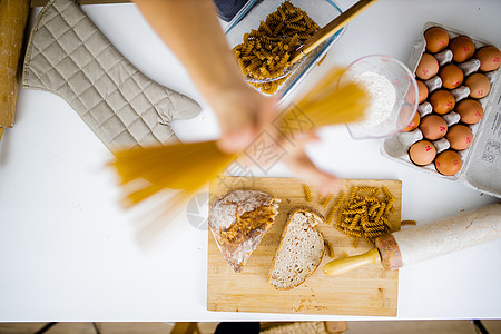 女性手持未经烹煮的意大利面 其成分高于表格中的成分砧板碳水食物小吃面粉面条面包美食塑料利面图片