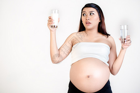 孕妇手里握着牛奶和水杯子的孕妇;一高清图片素材