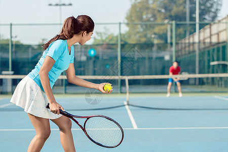 在网球比赛期间 职业女性运动员在服务时笑着微笑马尾辫长发玩家爱好蓝色女士男人动机地面运动图片