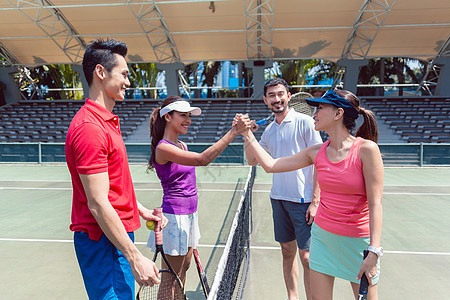 四个年轻的网球选手在一场双人混合比赛之前携手合作图片