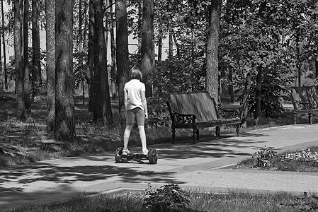 女孩骑着自行平衡的摩托车在公园里骑着环境木板树木均衡横杆电池户外运动力量娱乐运输图片