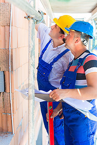 建筑工人在现场检查质量的工件工作墙壁建设者气泡男性安全帽头盔就业工人建筑图片