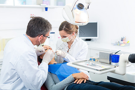 有牙医的病人牙科治疗医生男人手套牙科学工作面具手术钻孔女士助理图片