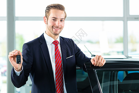 汽车经销业中的年轻人或汽车经销商钥匙推销员工作套装白色销售量男人服务咨询零售图片