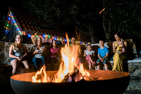一家家庭在火前举行烧烤晚会背景图片