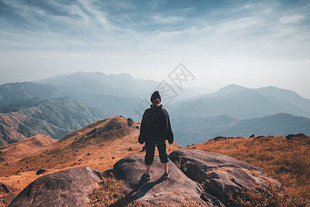 徒步山一个站在斜坡上的女人 美丽的山风景远足悬崖旅游冒险天空太阳自由活动幸福岩石背景