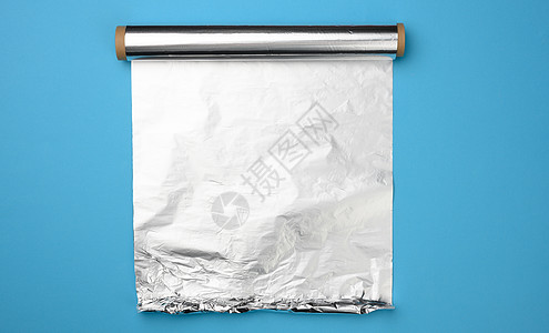 糙米卷蓝色背景上的灰色浮盘的无包装卷反射床单包装银色折叠灰色光泽度金属皱纹背景