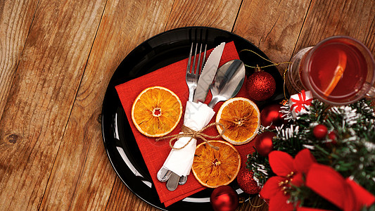 圣诞晚餐装饰 配有干橙子和黑色餐盘上的红餐巾纸装饰品桌布庆典星星卡片刀具食物假期银器勺子图片