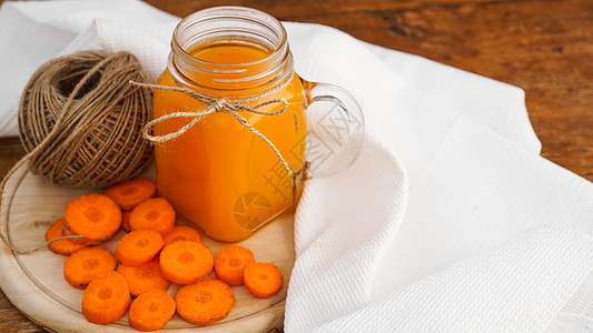 明亮橙红胡萝卜汁和木本底的麻绳饮食茶点片段果汁植物饮料橙子食物缠绕水壶图片