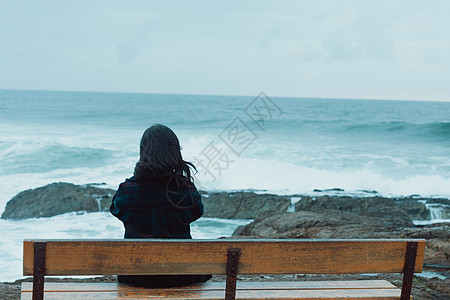 女人背对着摄影机 坐在长椅上 在大海前的巨型海洋和复制空间面前图片