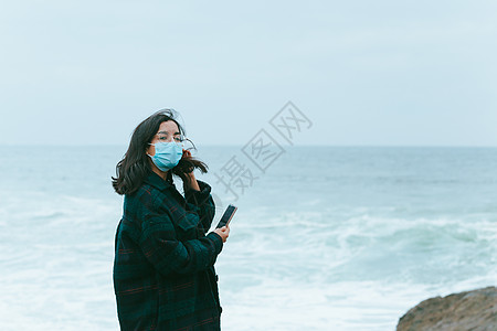 在大海前用手机时 戴面罩回头看女人的眼神图片