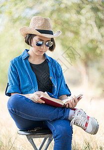 女人戴帽子 在椅子上看书闲暇公园自由学生乐器文学知识花园论文阅读图片