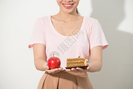 一只手的女孩有苹果 另一只手有一个蛋糕食物营养女性健康女士白色饮食垃圾绿色图片