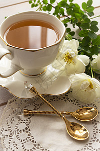 古老的古董彩陶 陶瓷 圆形陈年盘上镀金的瓷罐 带金汤匙的瓷茶杯中华丽的新鲜玫瑰花束背景图片