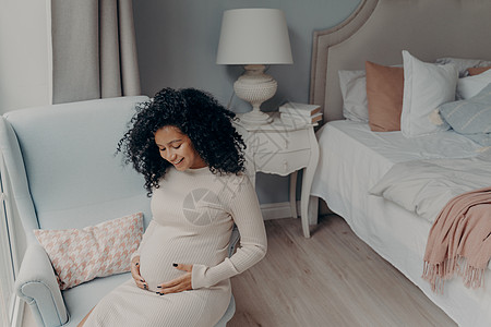 可爱的非裔美国人坐在卧室里 享受幸福怀孕和快乐生活图片