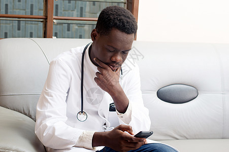 年轻医生在看他的手机技术导航专注互联网报告扶手椅男性数据展示心脏病学图片