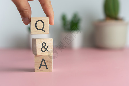 在木制立方体上 用有背景的手握着Q和字母表 问答的含义骰子社区商业服务教育男人顾客知识测验学习图片