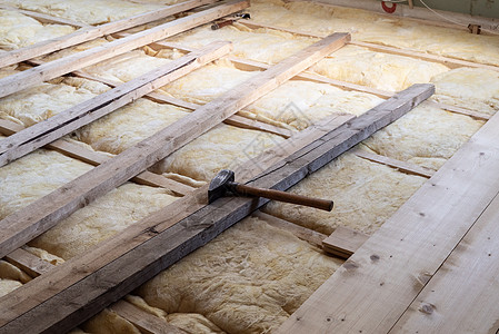 在玻璃羊毛顶上铺木板地板 用木制铁锤进行温暖绝缘 以修复家用地板图片
