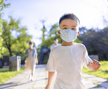 快乐的小男孩戴着医疗面具 与父母一起在公园里散步学校父亲妈妈学生女士暴发面具男人家庭保健图片