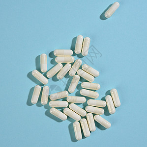 蓝色背景上白色胶囊中的药用粉末 治疗丸 营养补充剂药片止痛药处方药店药品药剂治愈抗生素剂量制药图片
