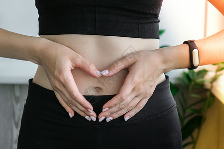 手在健康和苗条的腹部女人的心形符号 健身健康理念 身体护理 怀孕 减肥饮食概念 有肠道或生殖问题的妇女图片